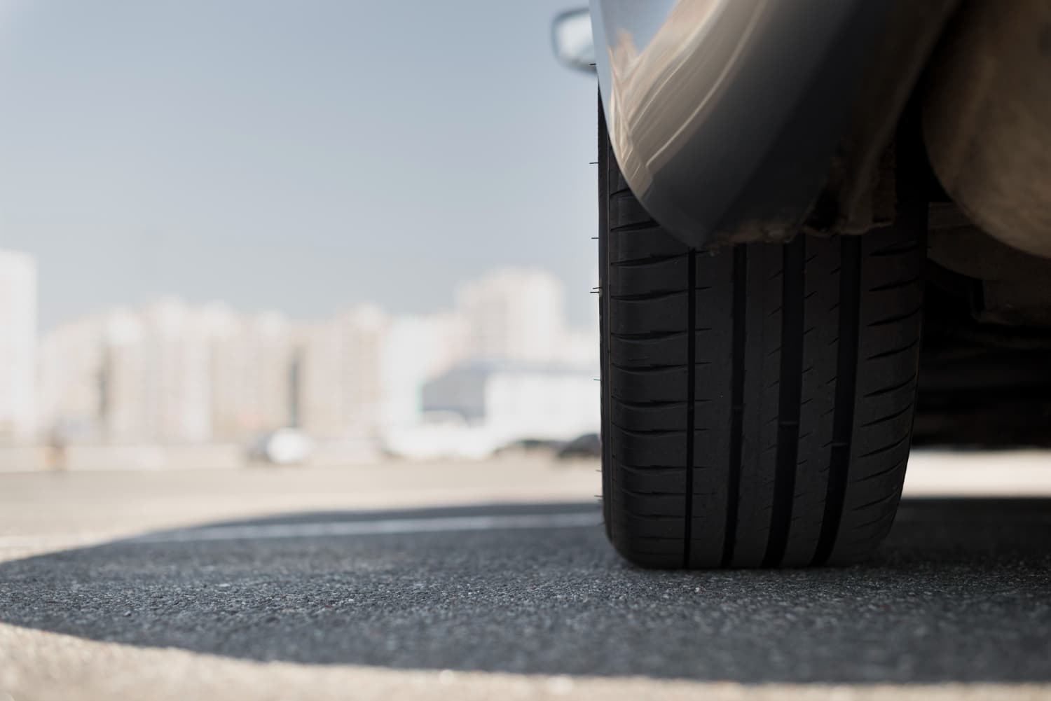 CDW Insurance Included - Drive Confident in Iceland | Free Extras & Flexible Cancellation Close-up of a car tire with fresh tread on asphalt in a city parking lot, illustrating safety and road readiness for Iceland campervan rentals.