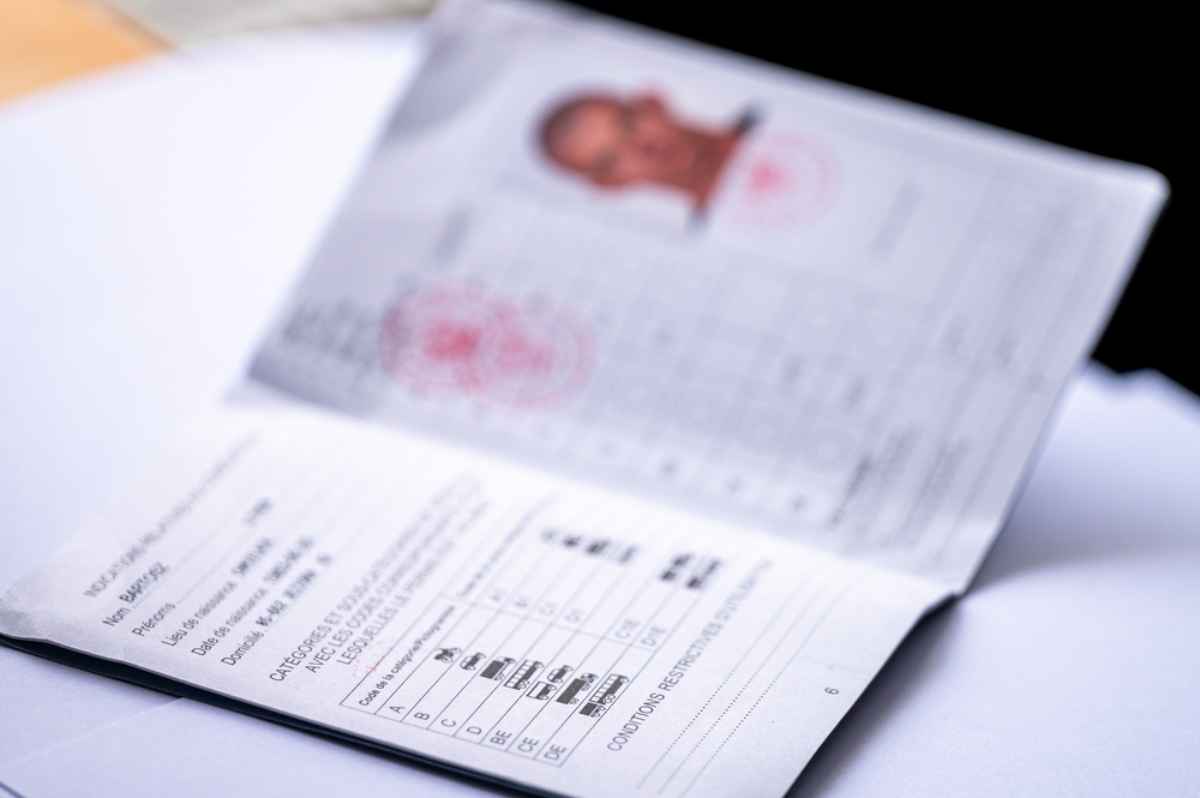 Open passport on a table, showing personal details and photo. Focus is on text with a blurred background, creating a formal setting.